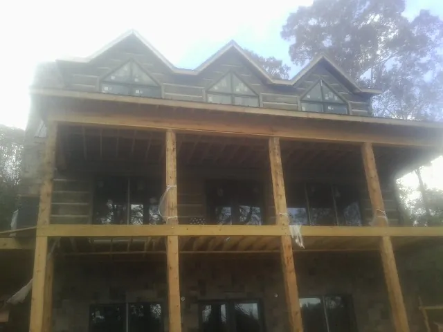 Dormers and porch framing on a large log home under construction — Roof Coating work by our crew in Poseyville