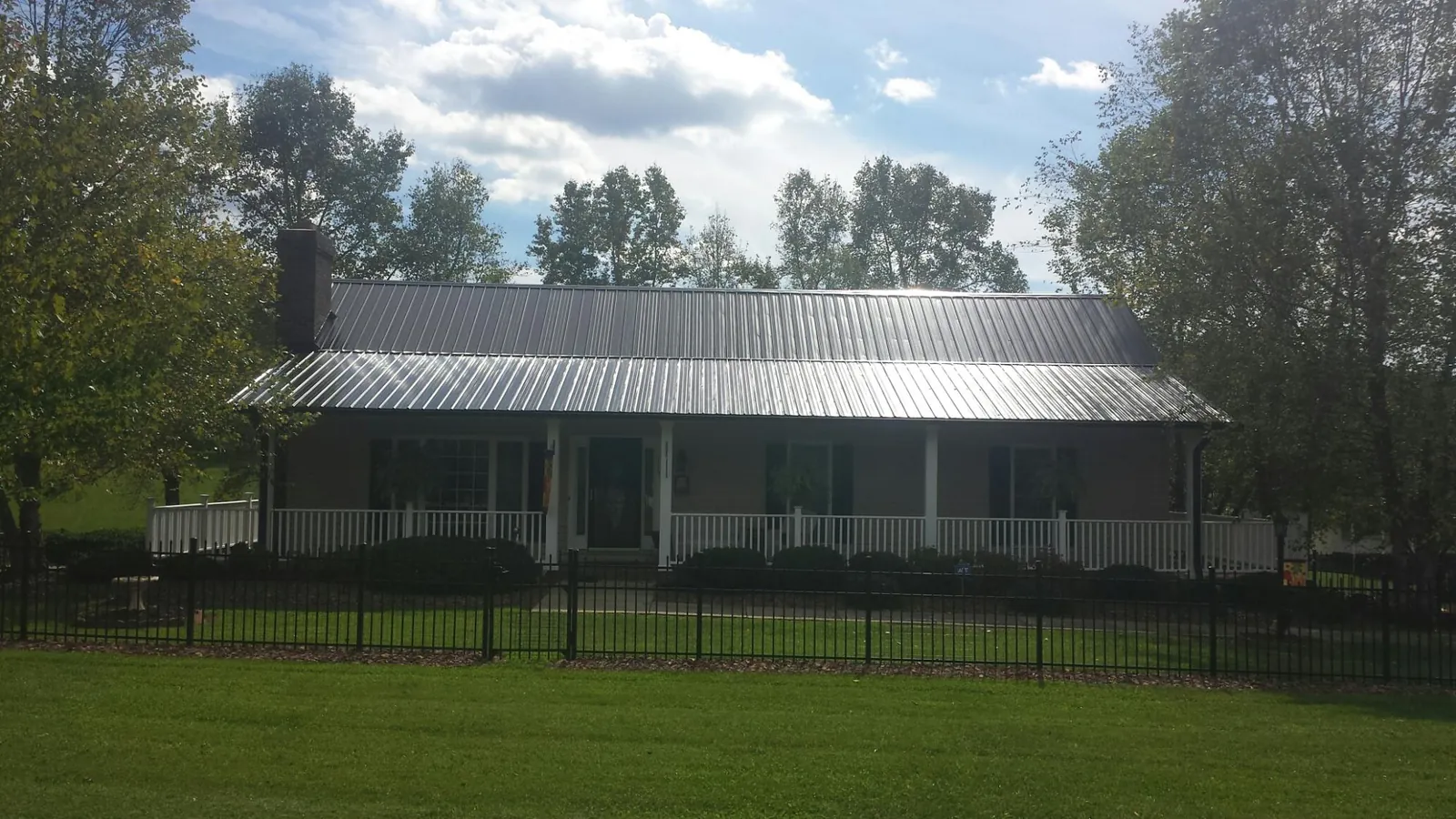Gray metal roof on a brick ranch with a full width front porch — Gutter Guard Installation work by our crew in Poseyville