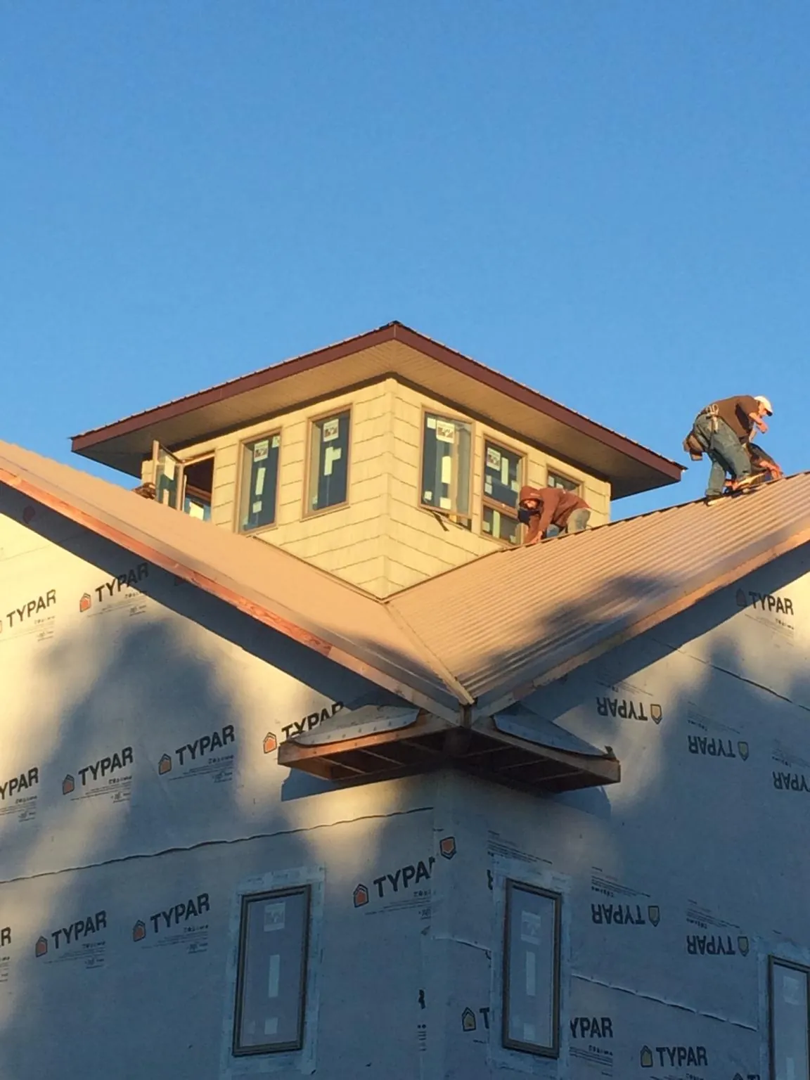 Roofers working around a rooftop cupola on a new metal roof at sunset — Roof Waterproofing in Poseyville by Roofing Brothers